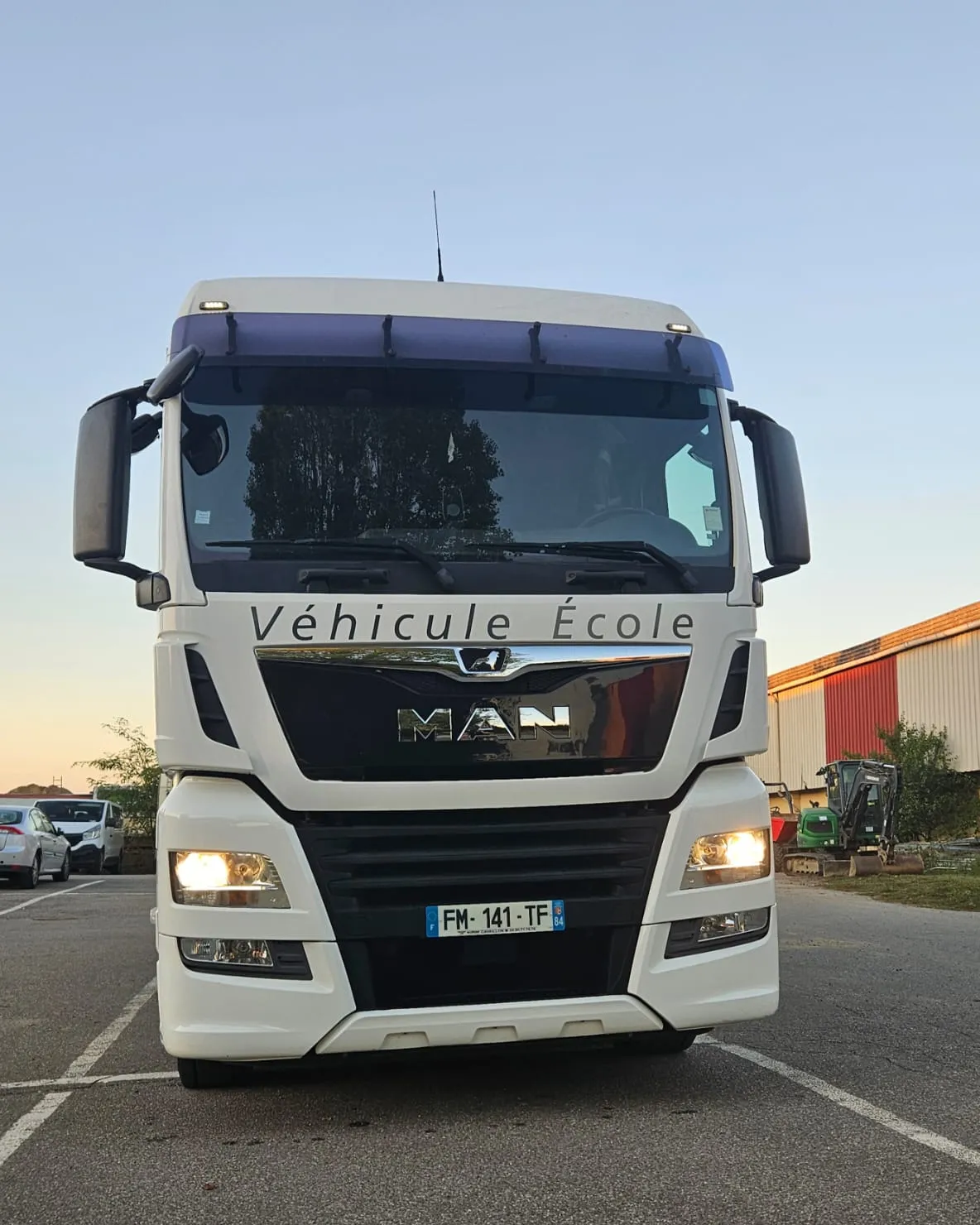 Le porteur MAN TGX de face, phares allumés, sur le parking du centre.