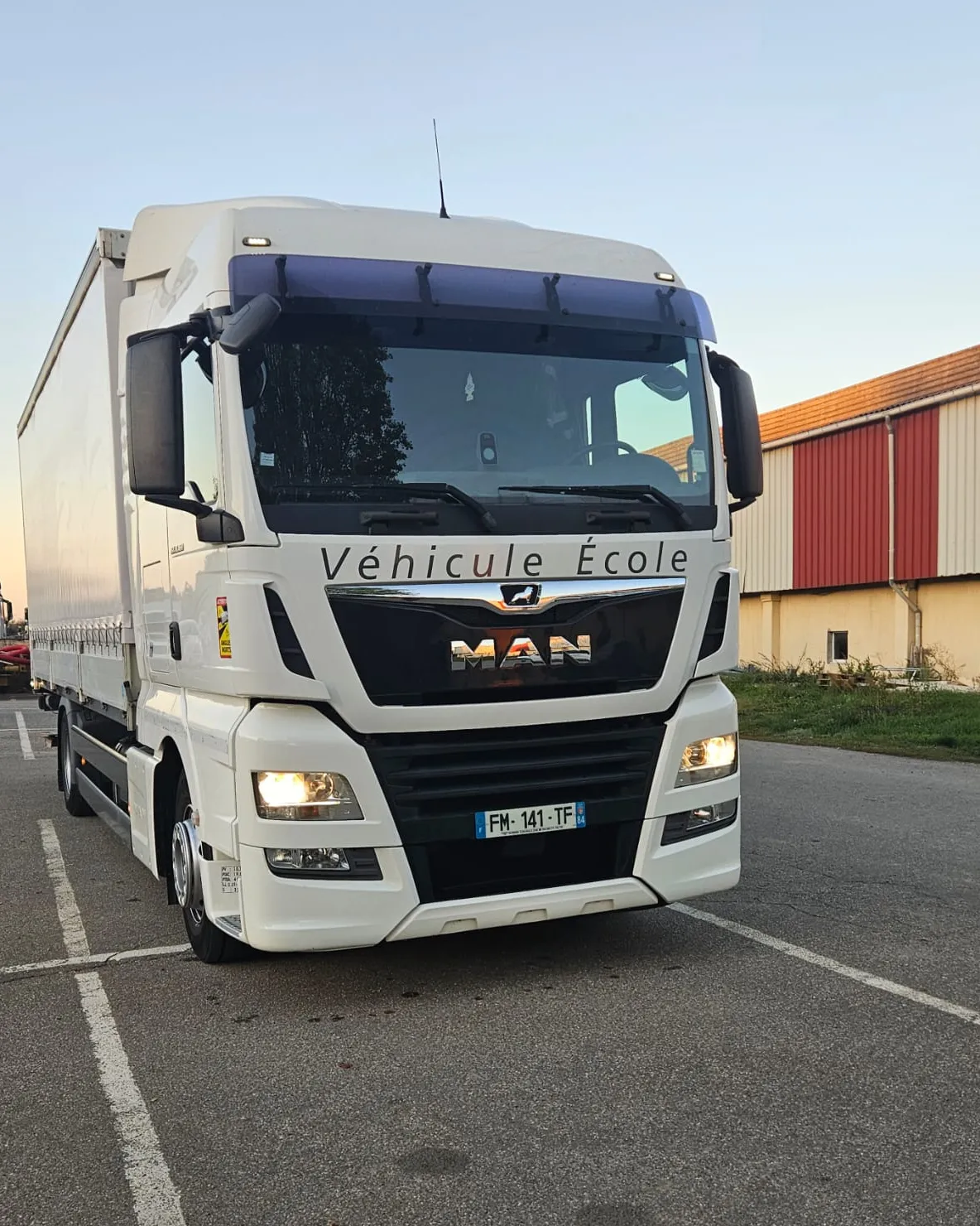 Le porteur MAN TGX du centre, vu de trois quarts avant, marqué « Véhicule École » sur la calandre.